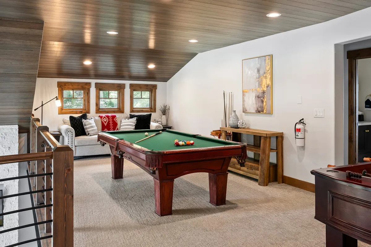 A cozy, inviting loft featuring a billiard table as the focal point, complemented by a comfortable sofa and stylish artwork on the wall. The space radiates warmth and encourages social interaction, perfect for friendly games of pool and relaxed hangouts.