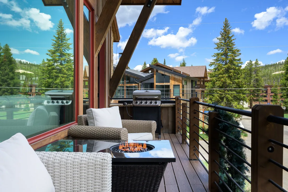 This exterior image showcases an inviting outdoor seating area with a fire pit, mountain views, and a gas grill—set against a stunning natural backdrop. The arrangement hints at both cozy gatherings and alfresco dining, with the grill and fire pit serving as focal points for relaxation and entertainment.